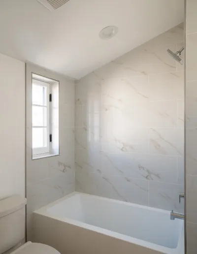 A white bathroom with a tub and toilet.
