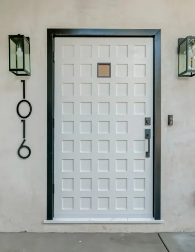 A white front door with two lights on it.