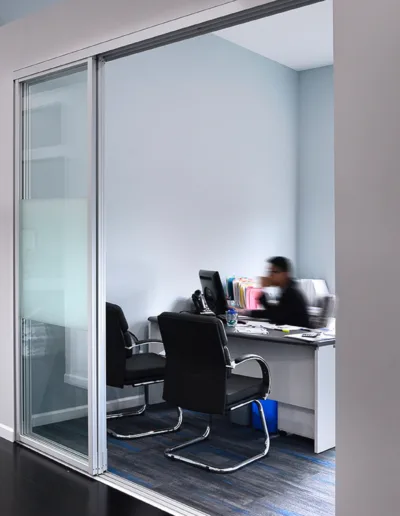 An office with glass doors and a desk.