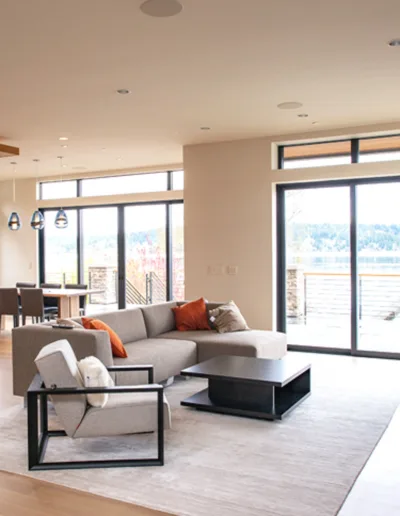 A modern living room with hardwood floors and large windows.