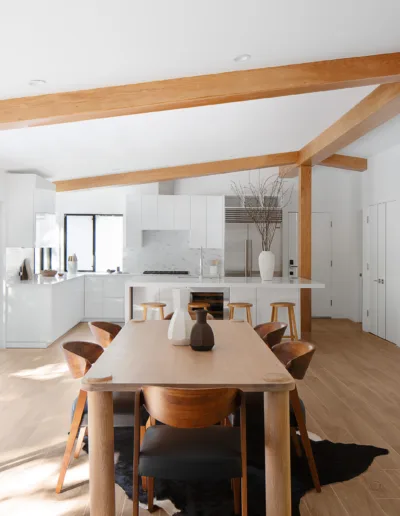 A modern kitchen with wood beams and a dining table.